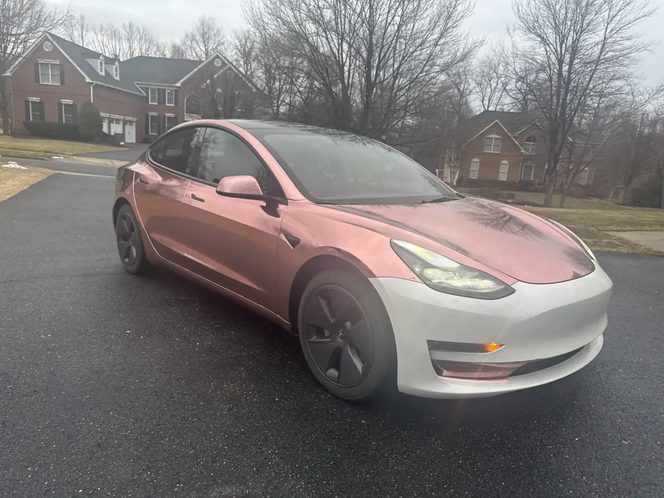 A Model 3 with everything but the front bumper done. The bumper is the factory finish, the rest is rose gold chrome, and the two are eighteen inches apart in the same afternoon light.